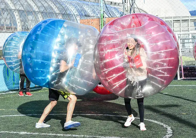 Grupo de amigos riendo mientras juegan fútbol burbuja en Bumperz Colombia, Bogotá.