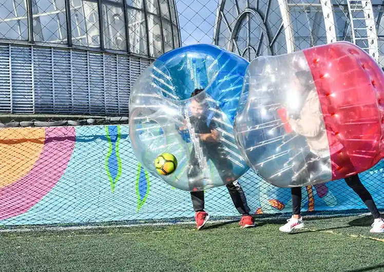 Acción y diversión en un partido de fútbol burbuja para eventos corporativos.