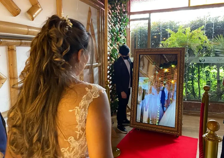 Pareja de novios usando el Espejo Mágico photobooth en su boda.
